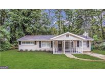Charming single-story home with a welcoming porch, surrounded by lush greenery and a well-manicured lawn at 3395 Longleaf Dr, Decatur, GA 30032