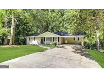 Charming single-story home with a large driveway and lush green lawn surrounded by mature trees at 3558 Turner Heights Dr, Decatur, GA 30032