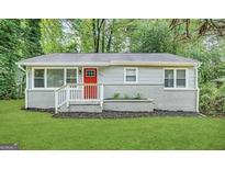 Charming single story home featuring a manicured front lawn and cheerful red front door at 2000 Marvin Sw Ln, Atlanta, GA 30311