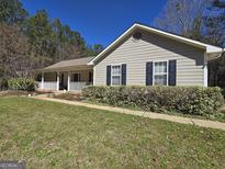Charming single-story home with a welcoming porch, neat landscaping, and classic black shutters at 180 Collins Way, Locust Grove, GA 30248