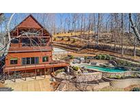 Stunning three-story log home featuring a large deck and swimming pool with terraced landscaping at 5735 Archer Ave, Cumming, GA 30041