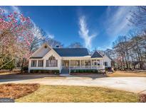 Beautiful exterior elevation of a home with large front porch and circular driveway and a lush landscaped yard at 3140 Cox Cemetery Rd, Social Circle, GA 30025