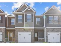 Newly constructed townhome features a brick facade, attached garage, and covered entryway at 223 Ivey Ter # 34, Temple, GA 30179