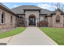 Beautiful brick home featuring an arched doorway, manicured lawn, and a long concrete driveway at 1198 Elliot Rd, Mcdonough, GA 30252