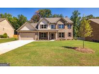 Charming brick home featuring a well-manicured lawn, covered entryway, and a two-car garage at 204 Shelton Dr, Mcdonough, GA 30252