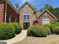 Charming home with a stone and brick facade, arched windows, and beautifully manicured landscaping at 1209 Persimmon Way, Mcdonough, GA 30252