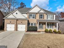 Inviting two-story home with a brick facade, charming front porch, three-car garage, and manicured landscaping at 2536 Kachina Trl, Dacula, GA 30019
