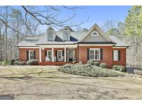 Charming brick home boasts rocking chair front porch and lush, mature landscaping at 190 Postwood Dr, Fayetteville, GA 30215