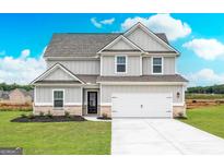 Charming two-story home featuring gray siding, a two-car garage, and a beautifully landscaped front yard at 1013 Claas Way, Locust Grove, GA 30248