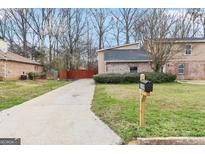 Traditional home featuring a spacious driveway, mature trees, and a welcoming yard at 2589B Se Fieldstone View Ln, Conyers, GA 30013
