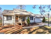 Charming single-story home featuring a metal roof, light siding and welcoming front porch and a driveway leading to a one-car garage at 1068 Little Vine Church Rd, Villa Rica, GA 30180