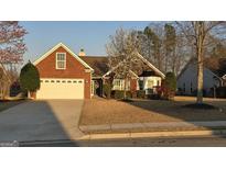 Charming brick home featuring an attached two-car garage and a blossoming tree in the landscaped front yard at 1006 Harbor View Ln, Mcdonough, GA 30252