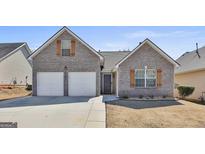 Charming brick home featuring a two-car garage, complemented by wood shutters and a well-manicured lawn at 1747 Deer Crossing Cir, Jonesboro, GA 30236