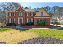 Charming brick home featuring a manicured lawn, mature trees, and inviting curb appeal at 707 Orleans Trce, Peachtree City, GA 30269