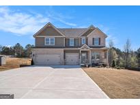 Two-story home featuring a two-car garage, neutral paint, brick accents, and a well-manicured lawn at 157 Donovan Ave, Locust Grove, GA 30248