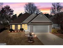 Charming single-story home featuring a manicured lawn, two-car garage, and inviting exterior lighting at 1160 Strath Clyde Way, Mcdonough, GA 30253