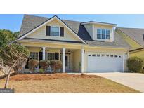 Charming, light yellow home featuring a two-car garage, covered front porch and tidy landscaping at 252 Turnbridge Cir, Peachtree City, GA 30269
