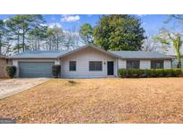 Charming single-story home with a gray roof, complemented by manicured landscaping and mature trees at 1463 Rockmoor Ct, Stone Mountain, GA 30088
