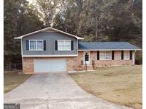 Charming split-level home with brick facade, two-car garage, and spacious driveway on a lot filled with mature trees at 4775 Cold Creek, Conyers, GA 30094