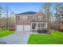 Charming two-story brick home with a welcoming front porch and two-car garage, nestled on a well-maintained lawn at 13699 Inman Rd, Hampton, GA 30228