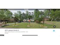 Charming two-story home with white siding, a well-manicured lawn, and palm tree landscaping at 4970 Lakeland Woods Ct, Dunwoody, GA 30338