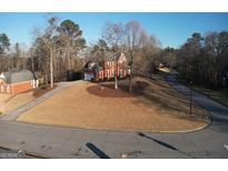 Brick home with attached garage on landscaped lot with circular driveway during winter at 5700 Thrasher Sw Ln, Conyers, GA 30094