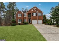 Traditional two-story brick home featuring a well-maintained lawn and two-car garage at 211 Mill Grove Sw Way, Smyrna, GA 30082