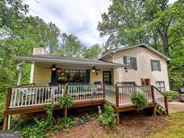 Charming home featuring a cozy front porch with ceiling fans, surrounded by lush trees and a well-manicured yard at 1972 Cox Dr, Austell, GA 30168