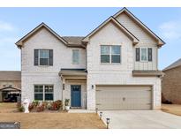 Two-story home with white brick, a beige garage door, and a blue front door at 445 Sawmill Trce, Hampton, GA 30228