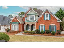 Charming brick home with green accents, landscaped yard, and inviting front porch at 2510 Shoreline Pkwy, Villa Rica, GA 30180