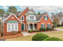 Charming two-story red brick home with green shutters and a well-manicured front yard at 2510 Shoreline Pkwy, Villa Rica, GA 30180