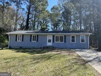 Charming one-story home with a well-maintained yard and classic blue siding and white trim, surrounded by mature trees at 357 Karen Ct, Lawrenceville, GA 30046