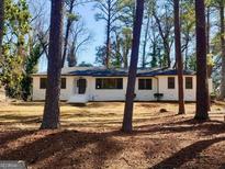 Charming, single-story home with a white brick exterior and inviting front entrance amid a wooded lot at 1332 Willis Mill Sw Rd, Atlanta, GA 30311