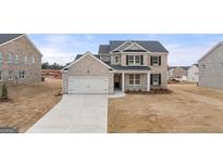 Charming two-story brick home with a two-car garage and manicured lawn on a sunny day at 1712 Goodwin Dr, Hampton, GA 30228