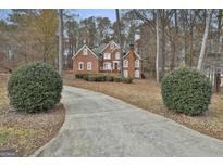 Charming two-story red brick home with well-manicured landscaping and a long driveway leading to the house at 165 Standing Oak Pl, Fayetteville, GA 30214