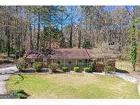 Charming home featuring a well-manicured lawn and a welcoming front porch, surrounded by mature trees and lush greenery at 9491 Hidden Branch Dr, Jonesboro, GA 30236