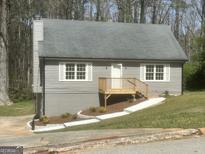 Charming gray split-level home featuring a front porch and freshly landscaped front yard at 3953 Woodland Se Cir, Conyers, GA 30013