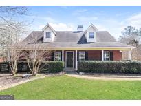 Charming brick home with dormer windows, lush landscaping, and inviting front entrance at 136 Leguin Forest Dr, Locust Grove, GA 30248
