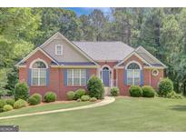 Charming brick home with a well-manicured lawn, blue shutters, and beautiful landscaping at 140 Rockglen Ct, Fayetteville, GA 30215