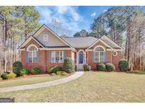Charming brick home with a manicured lawn, complemented by lush greenery and inviting curb appeal at 140 Rockglen Ct, Fayetteville, GA 30215