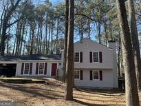 Charming two-story home with gray siding, red shutters, and a front yard surrounded by mature trees at 109 Park Cir, Stockbridge, GA 30281