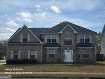 Charming two-story home featuring a symmetrical facade, arched window, neutral brick, and a well-manicured front lawn at 115 Portland Pl, Jonesboro, GA 30238