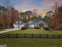 Charming home with a lush green lawn, tasteful landscaping and a picturesque black rail fence at 1080 Gaithers Rd, Mansfield, GA 30055