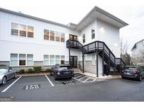 Modern white building with black stairs, complemented by ample parking spaces and manicured landscaping at 170 Fowler St # 200, Woodstock, GA 30188