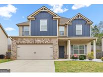 Charming two-story home with a brick and blue exterior, attached garage, and well-maintained lawn at 312 Maddi Grace Ct, Locust Grove, GA 30248