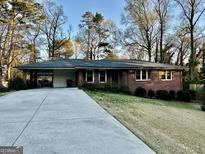Charming brick home featuring an attached carport and a well-maintained front yard with mature trees at 398 Lockridge Ln, Lawrenceville, GA 30046