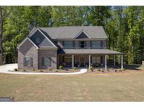 Beautiful two-story brick home featuring a welcoming front porch, shutters, and landscaped front yard at 830 Turner Rd, Mcdonough, GA 30252