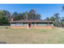 Charming single-story home featuring a brick and green exterior and well-maintained front lawn at 130 Thompson Rd, Tyrone, GA 30290