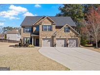 Traditional brick home with a three-car garage and a well-manicured front lawn on a sunny day at 2441 Noelle Ln, Powder Springs, GA 30127