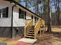 Charming home featuring traditional siding, a welcoming front porch, and new stairs nestled in a serene, wooded setting at 2211 Newborn Rd, Rutledge, GA 30663